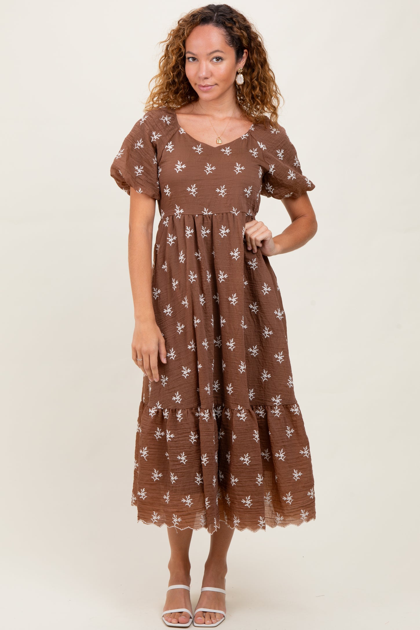 woman wearing a brown floral midi dress with puff sleeves and a tiered skirt