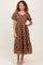 woman wearing a brown floral midi dress with puff sleeves and a tiered skirt