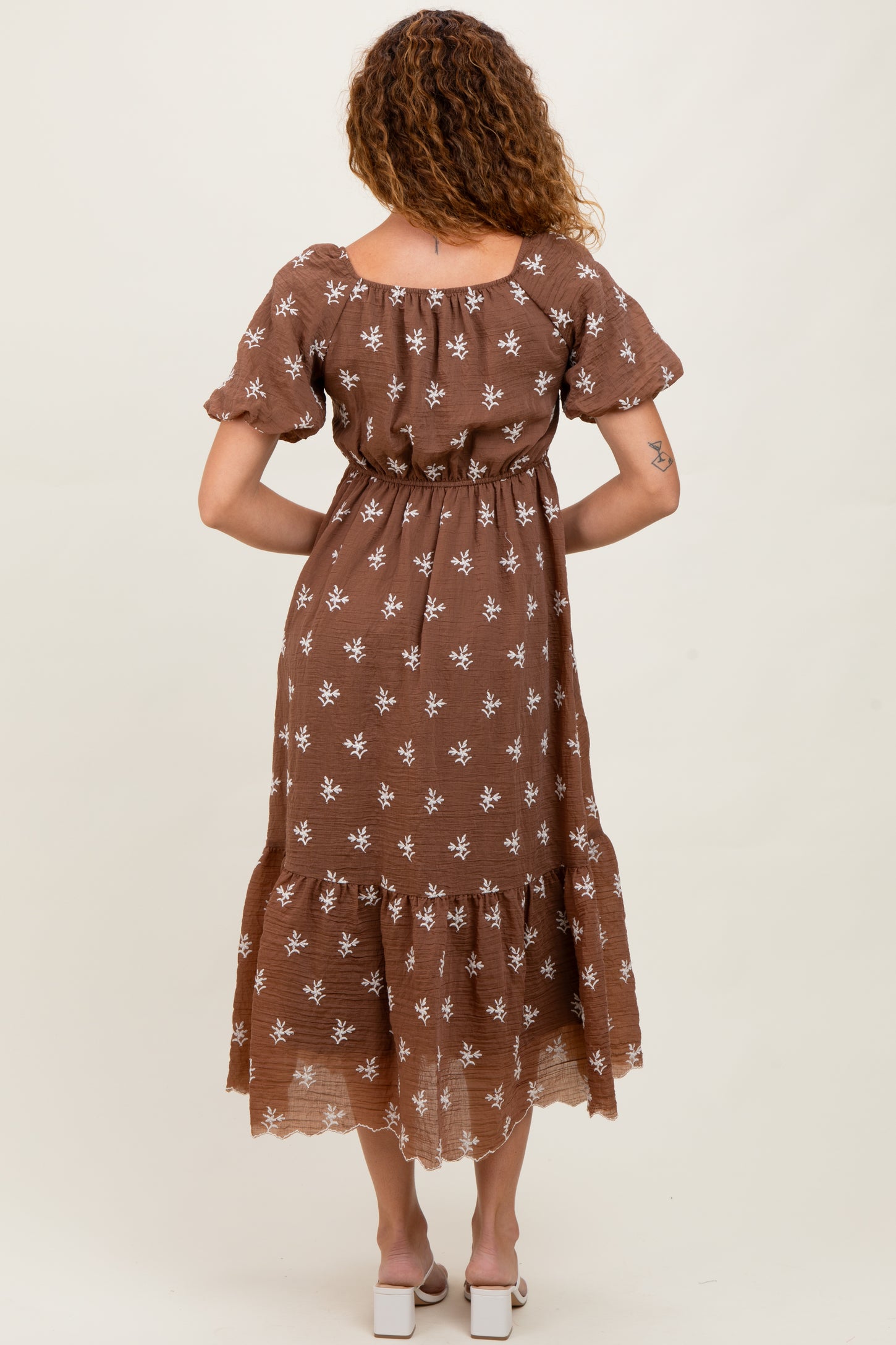 woman wearing a brown floral print maxi dress with short sleeves and a tiered skirt, seen from the back