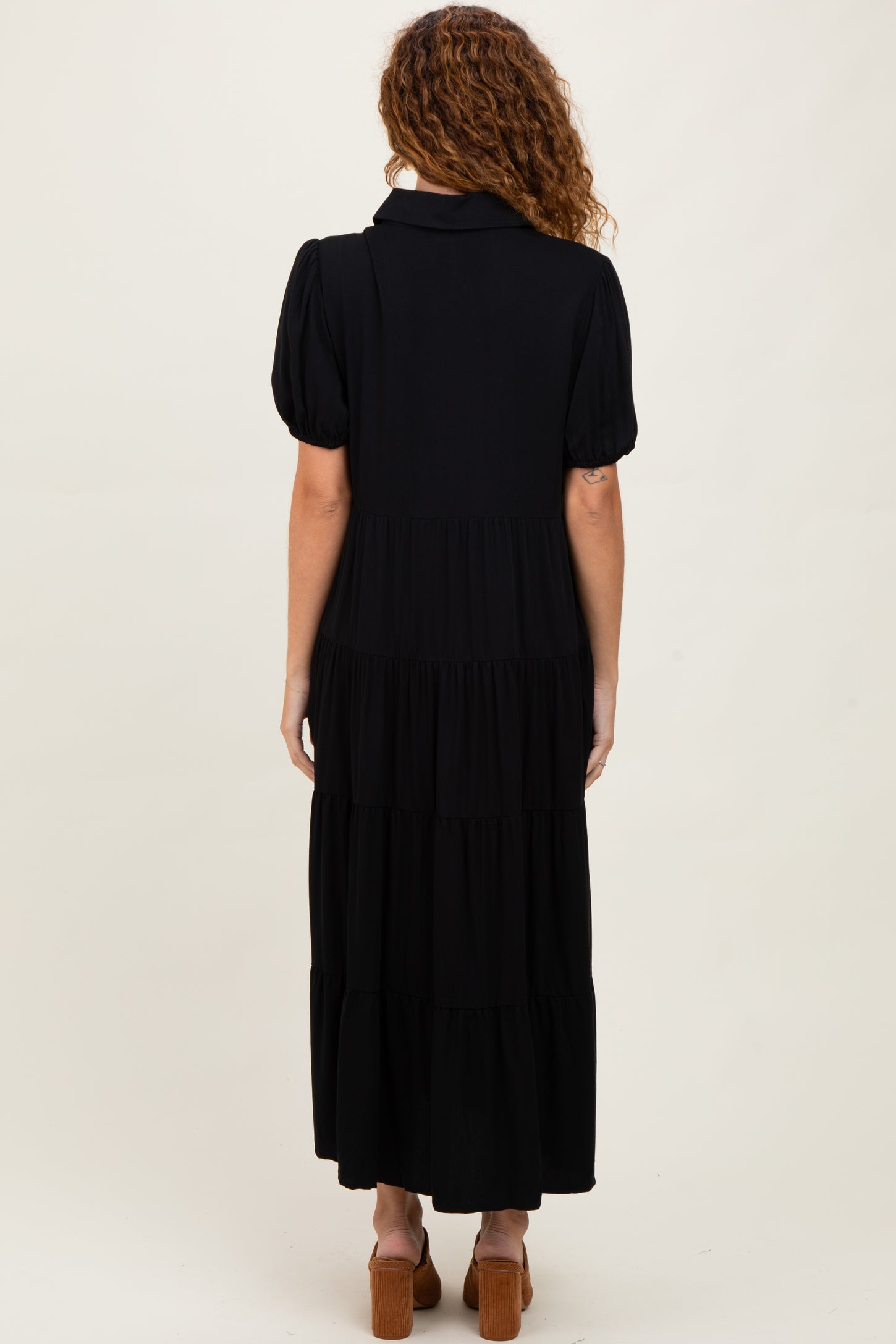 woman wearing a black tiered maxi dress with puff sleeves, shown from the back