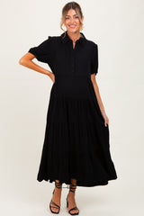 woman wearing a black tiered button-up maternity dress with short puff sleeves and a visible baby bump