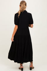 woman wearing a black tiered maternity dress with short puff sleeves, viewed from the back
