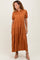 woman wearing a rust-colored tiered maxi dress with short puff sleeves and a collared neckline