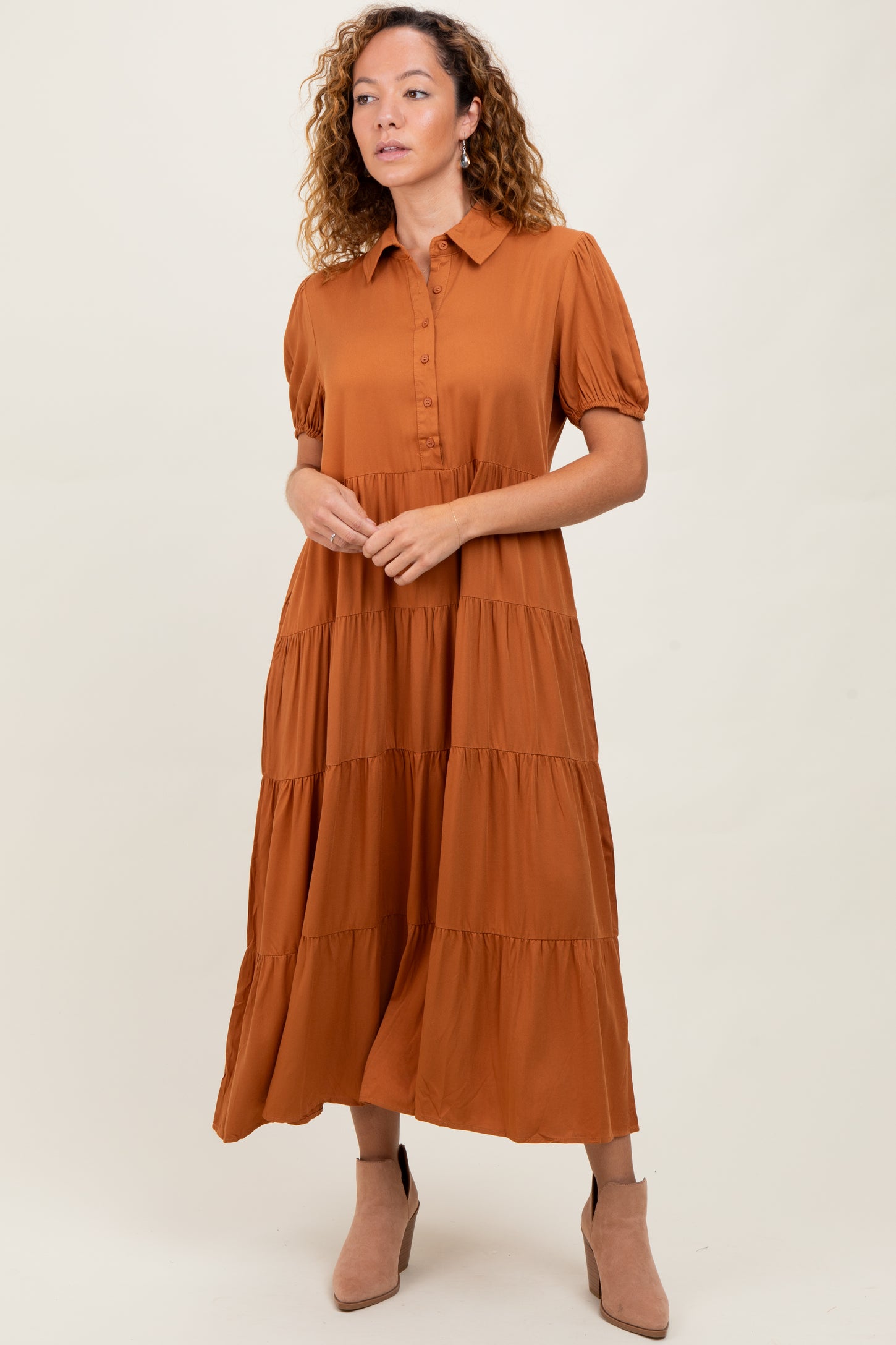 woman wearing a rust-colored tiered maxi dress with short puff sleeves and a button-up front