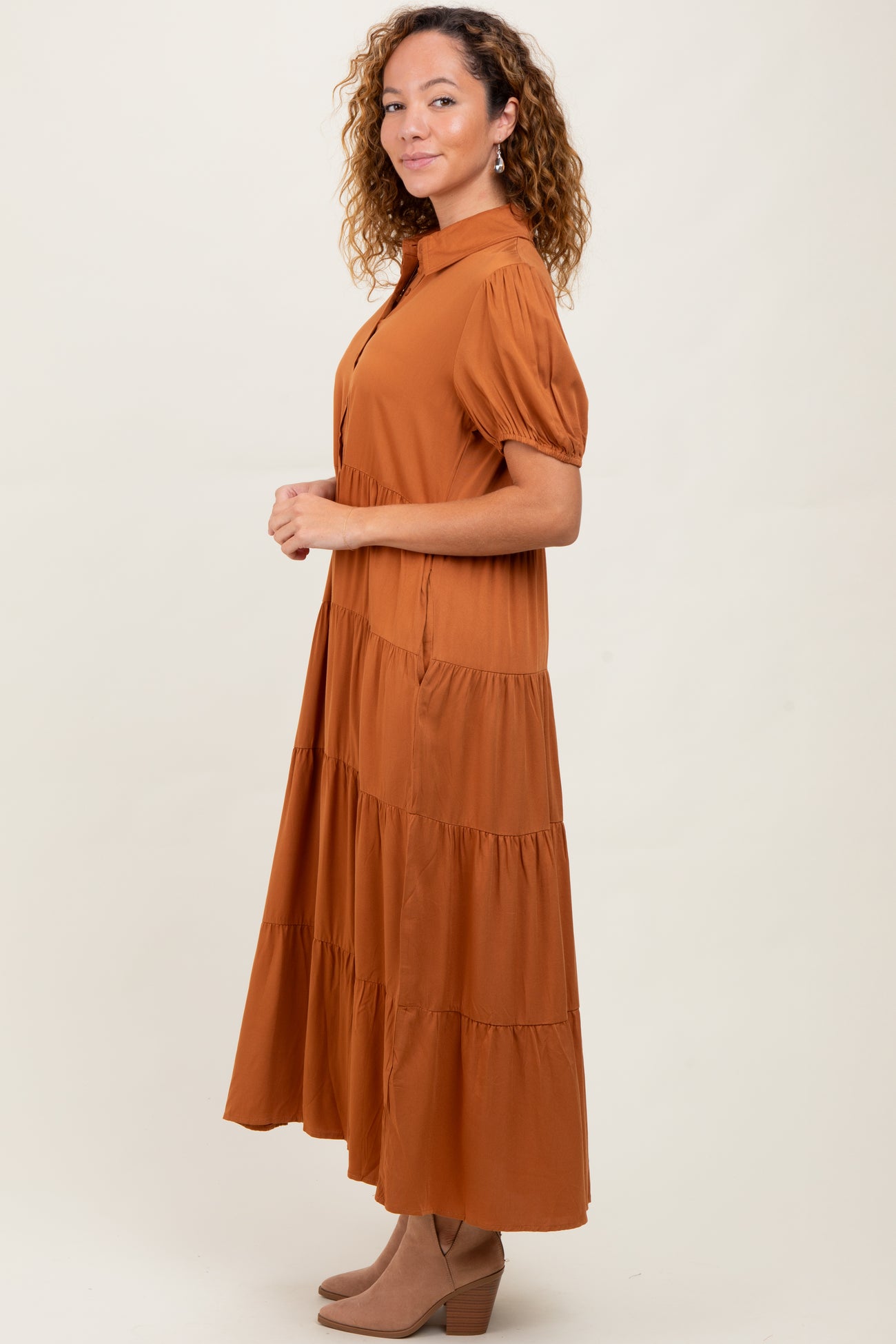 woman wearing a rust-colored tiered maxi dress with short puff sleeves and a high collar