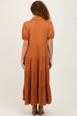 woman wearing a rust colored tiered maxi dress with puff sleeves and a collar, seen from the back