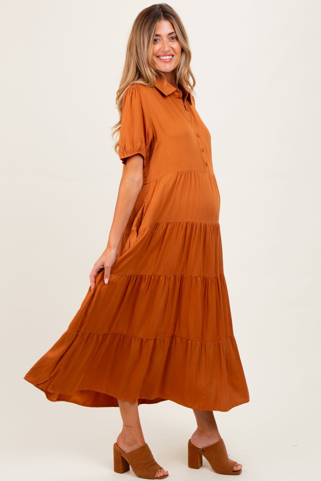 woman wearing an orange maternity maxi dress with short sleeves and a tiered skirt, showing her baby bump