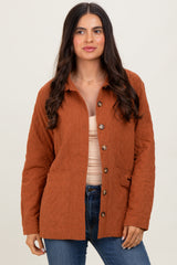 woman wearing a rust-colored quilted button-up jacket with two pockets over a beige top and blue jeans