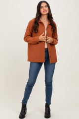 woman wearing an orange textured button-up shirt and blue skinny jeans
