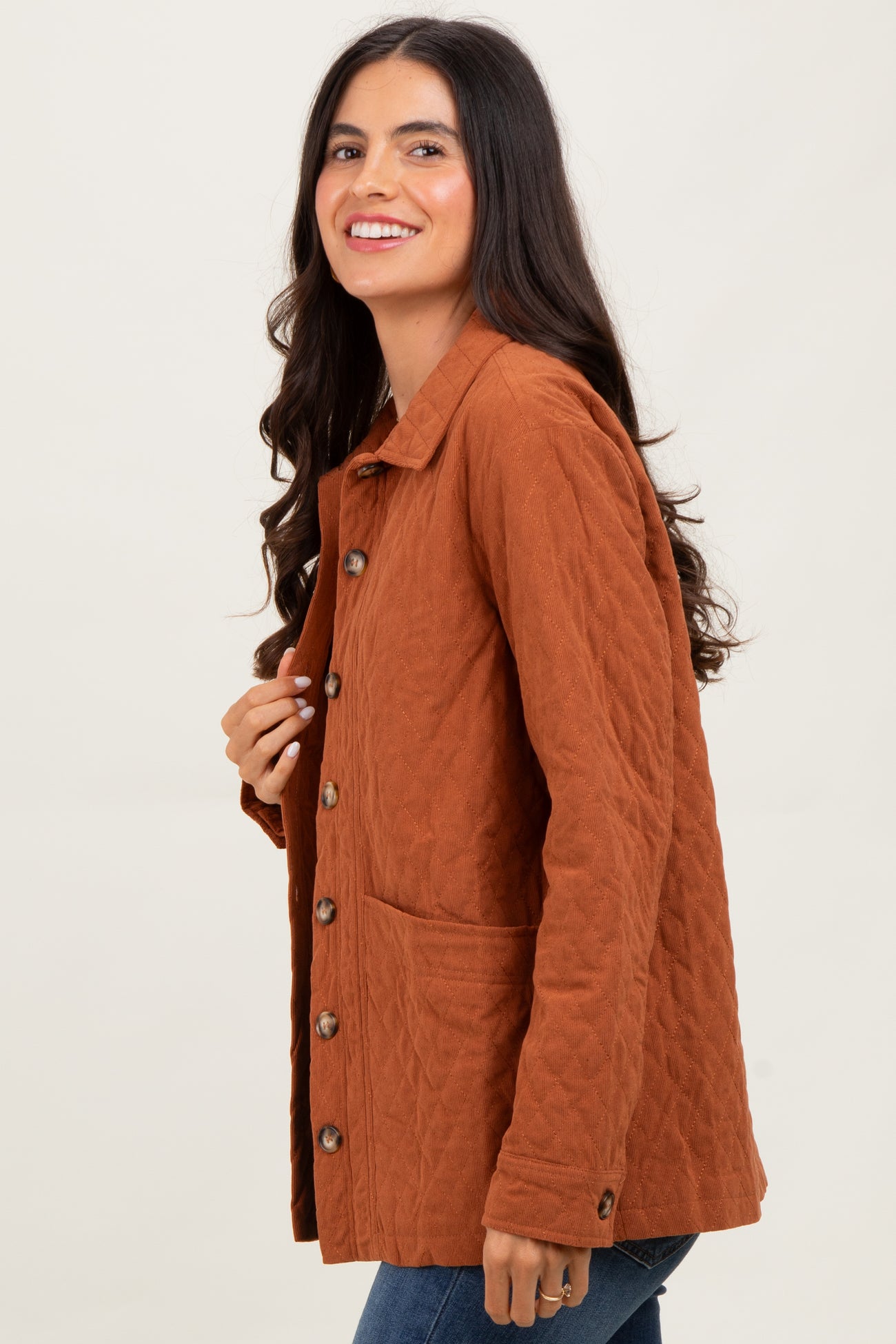 woman wearing a rusty orange quilted jacket with buttons and side pockets