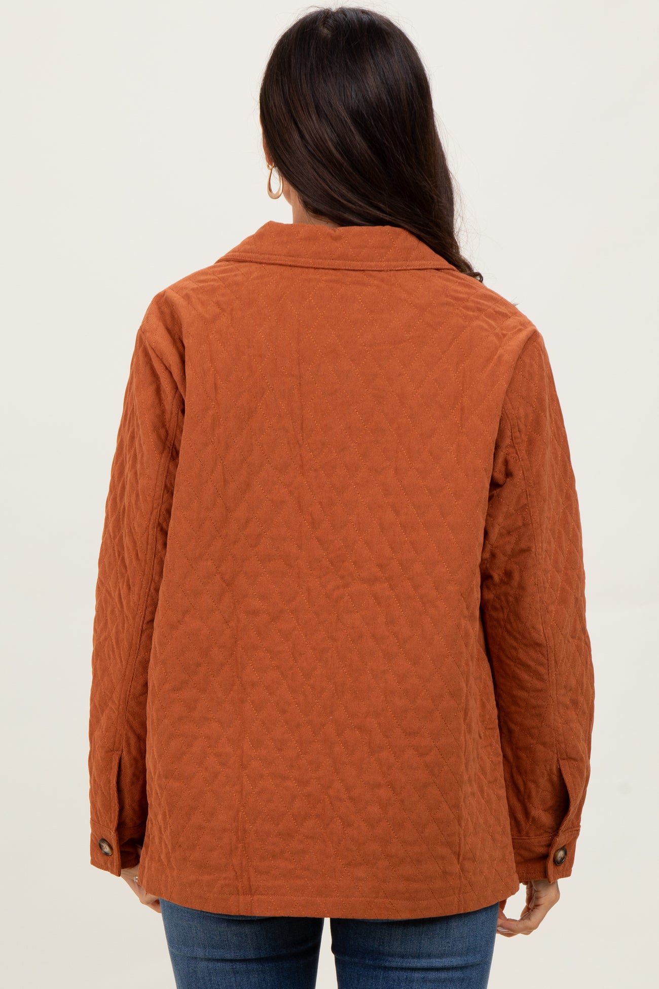 woman wearing a rust-colored quilted jacket with a collar, seen from the back