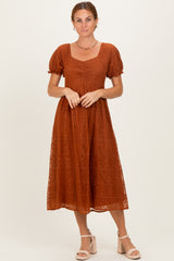 woman wearing a rust lace midi dress with short puff sleeves and a square neckline