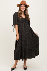 woman wearing a black maternity dress with white polka dots and puff sleeves, smiling and holding her baby bump