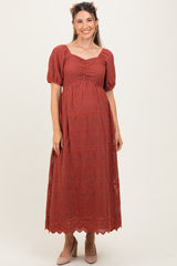 woman wearing a rust colored maternity maxi dress with puff sleeves and a gathered front, showcasing her baby bump