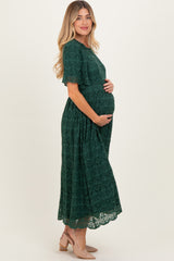 woman wearing a dark green lace maternity dress and holding her baby bump