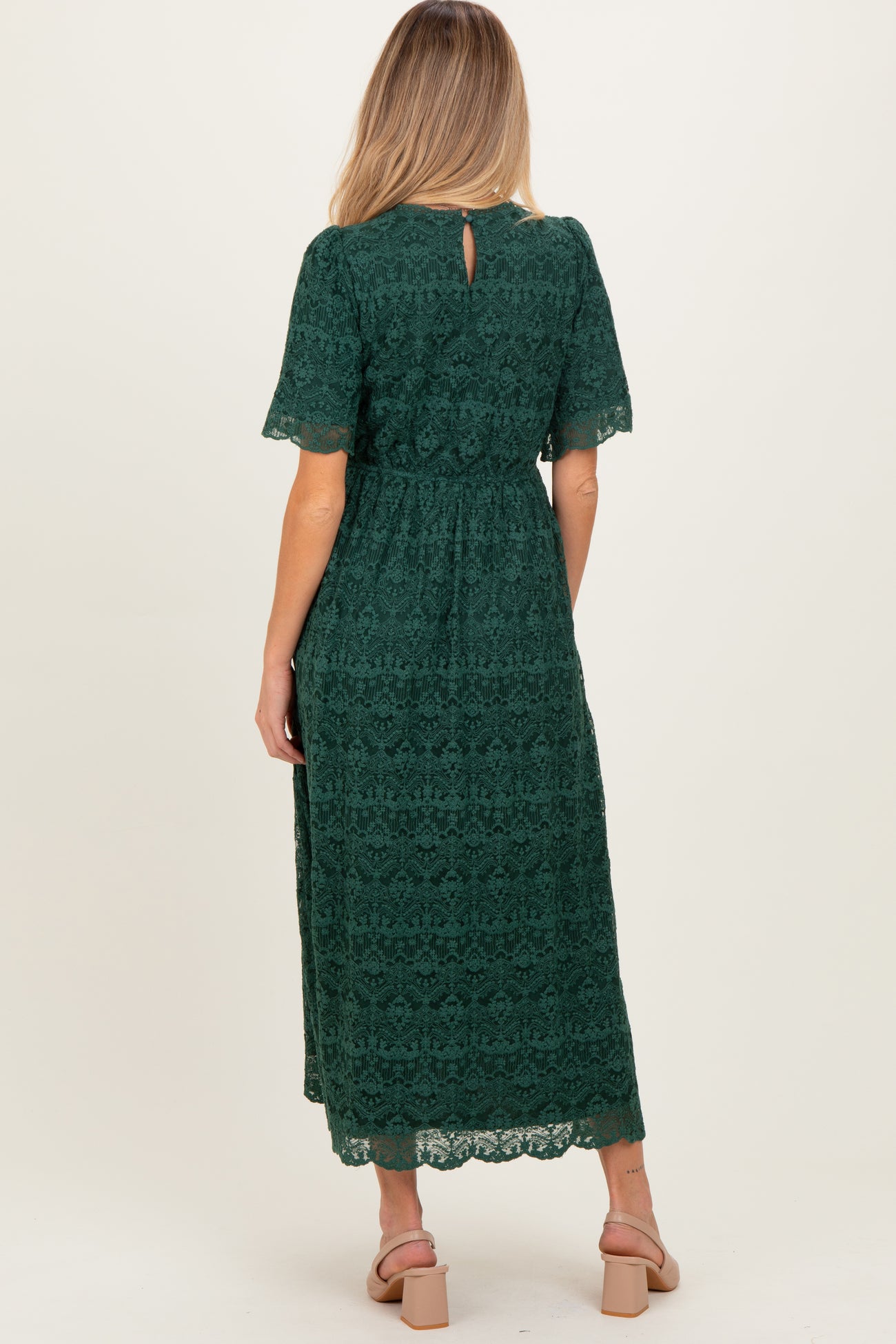 woman wearing a green lace maternity dress with a keyhole back and short sleeves