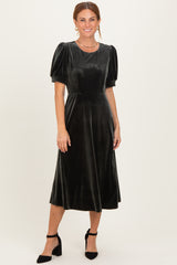 woman wearing a dark green velvet midi dress with puff sleeves and a fitted bodice, styled with black heels