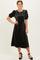 woman wearing a black velvet midi dress with puff sleeves and a fitted bodice, styled with black heels