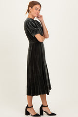 woman wearing a dark green velvet midi dress with puff sleeves and a fitted waist, paired with black heels