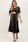 woman wearing a dark green velvet maternity dress with puff sleeves and a baby bump visible