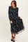 woman wearing a black floral long sleeve maxi dress with a smocked bodice and layered skirt, posing elegantly
