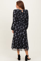 woman wearing a black floral midi dress with long sleeves and a tiered skirt, featuring a keyhole back detail