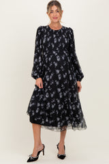 woman wearing a black floral print maternity dress with puff sleeves and a flowy skirt, showcasing a baby bump