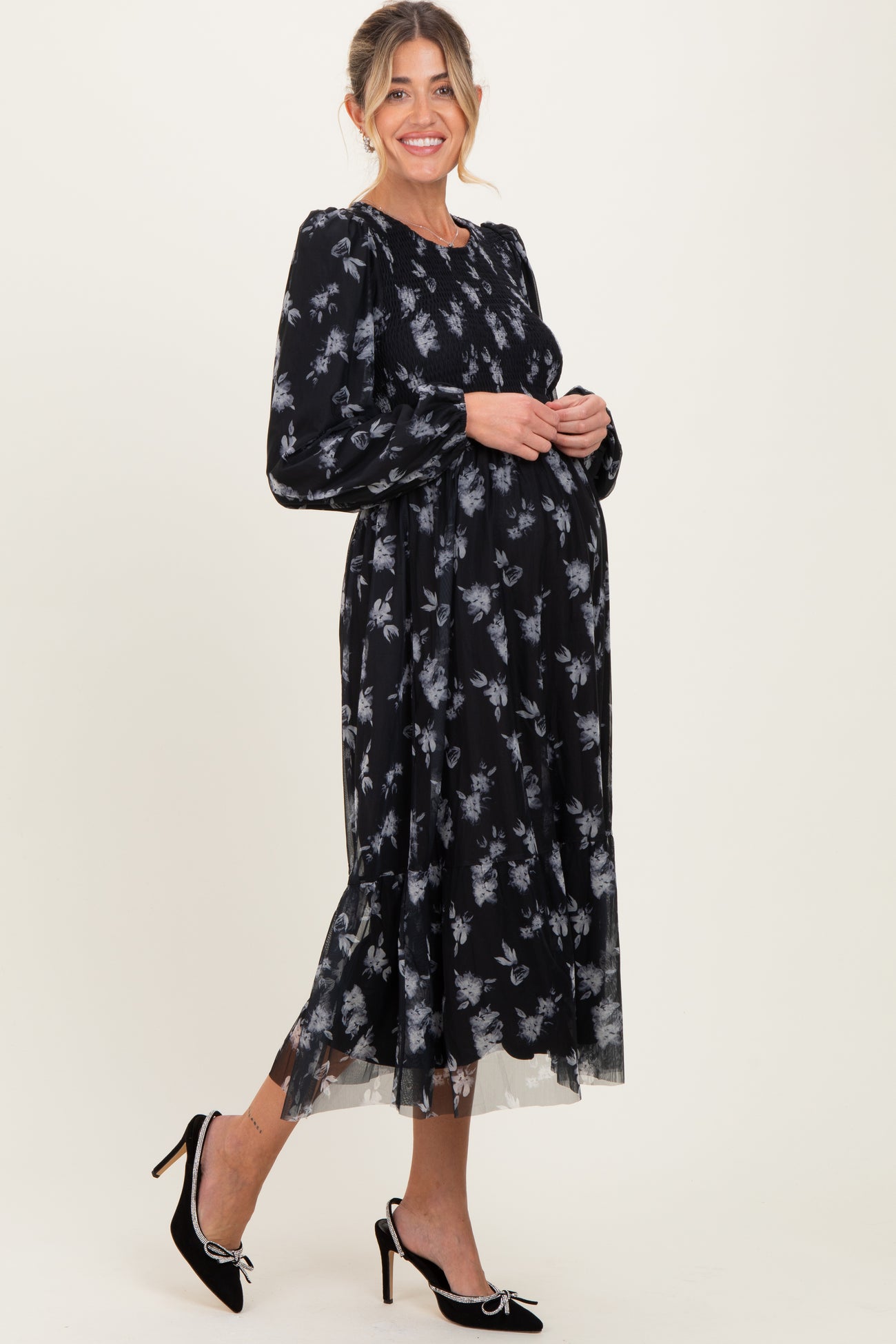 woman wearing a black floral maternity dress with long sleeves and a flowing skirt, showing her baby bump