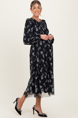 woman wearing a black floral maternity dress with long sleeves and a flowing skirt, showing her baby bump