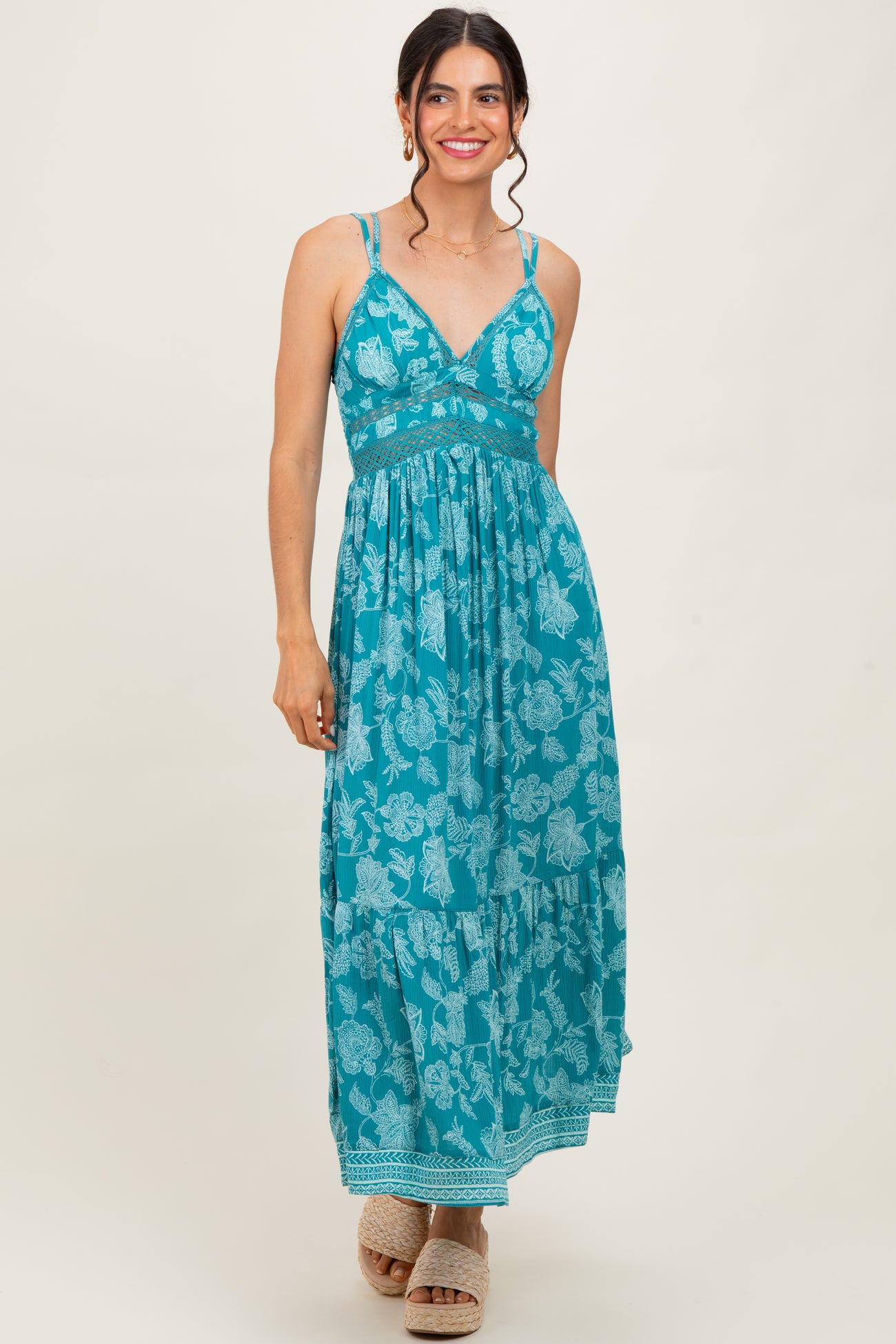 woman wearing a teal floral maxi dress with spaghetti straps and a tiered skirt
