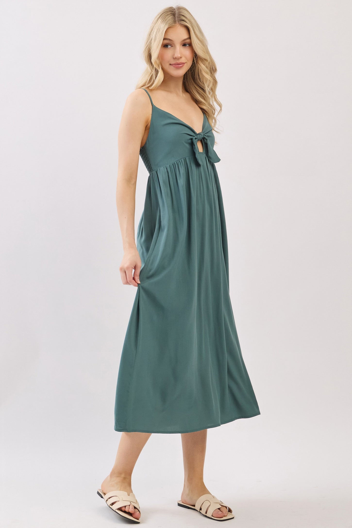 woman wearing a teal maxi dress with a tie detail at the bust and spaghetti straps