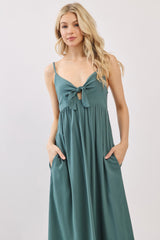 woman wearing a teal maxi dress with a tie-front detail and pockets, styled with spaghetti straps