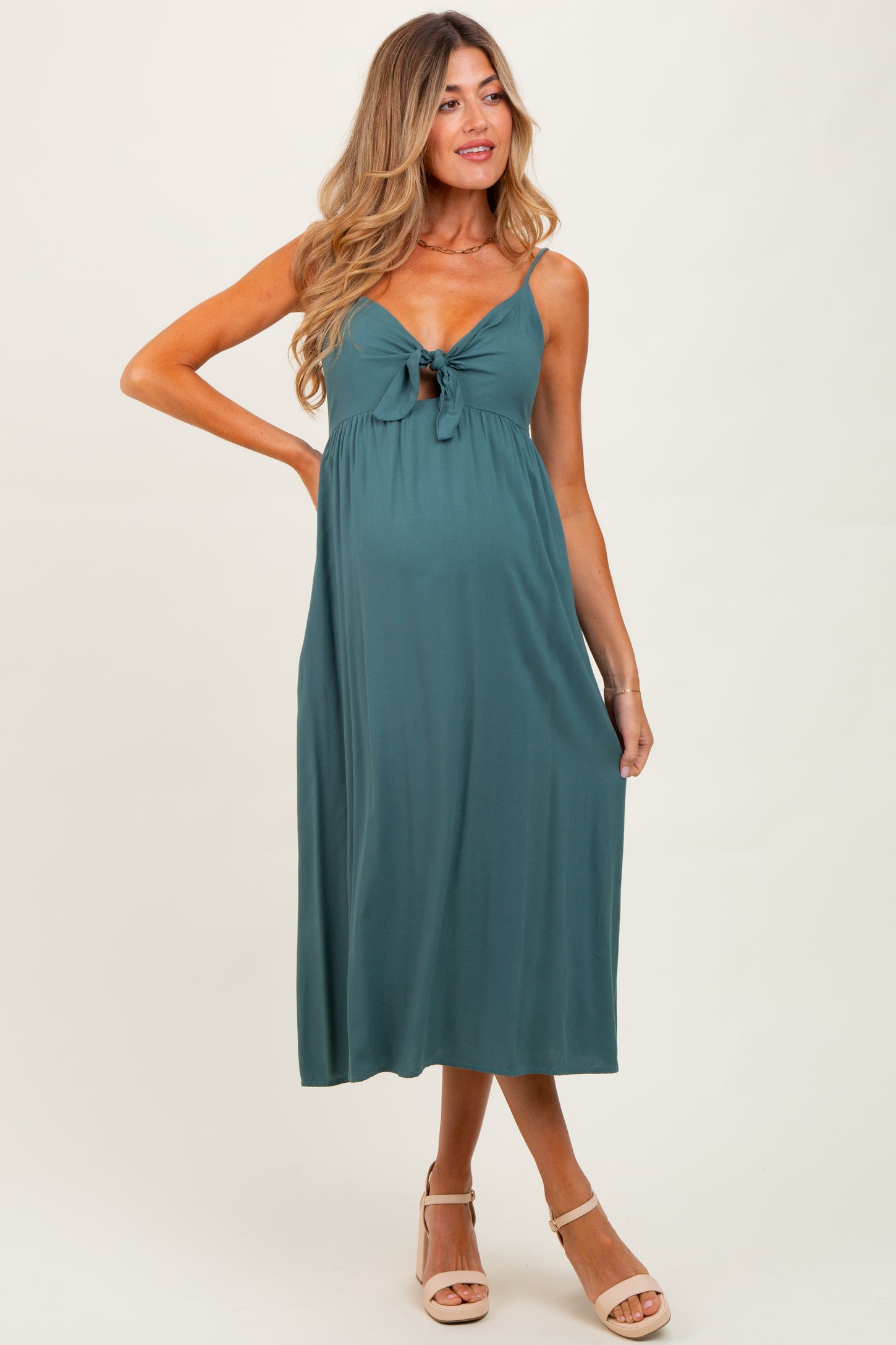 woman wearing a dark teal maternity dress with a front knot and a visible baby bump