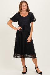 woman wearing a black lace detail midi dress with short sleeves and a square neckline