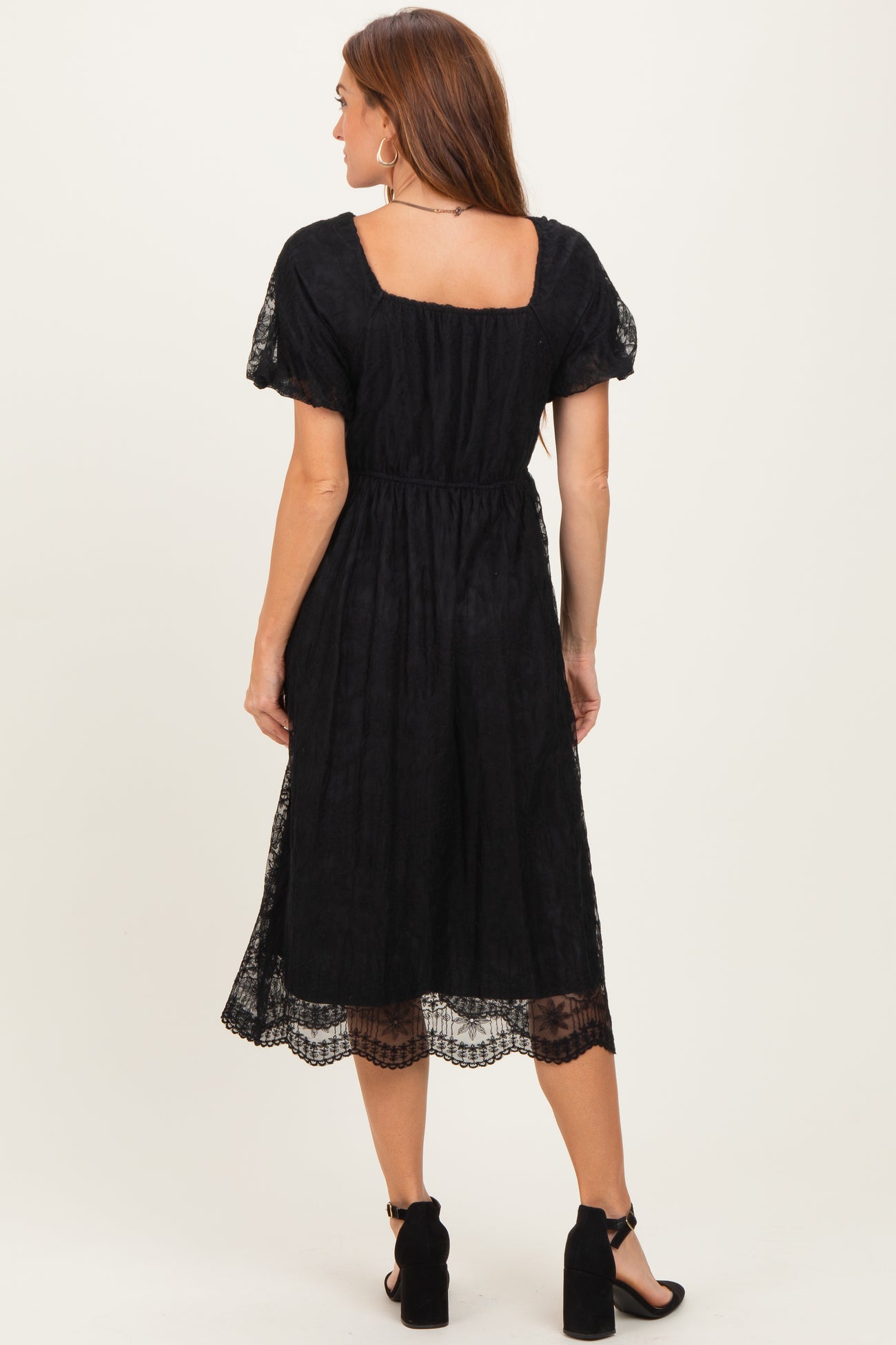 woman wearing a black midi dress with puff sleeves and lace trim, shown from the back