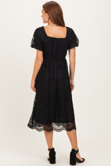 woman wearing a black midi dress with puff sleeves and lace trim, shown from the back
