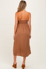 woman wearing a brown maternity dress with a smocked back and spaghetti straps, showing off a baby bump