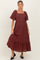 woman wearing a burgundy maternity dress with a square neckline and flutter sleeves, featuring a tiered hem