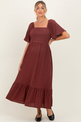 woman wearing a burgundy maternity dress with puff sleeves and a tiered skirt