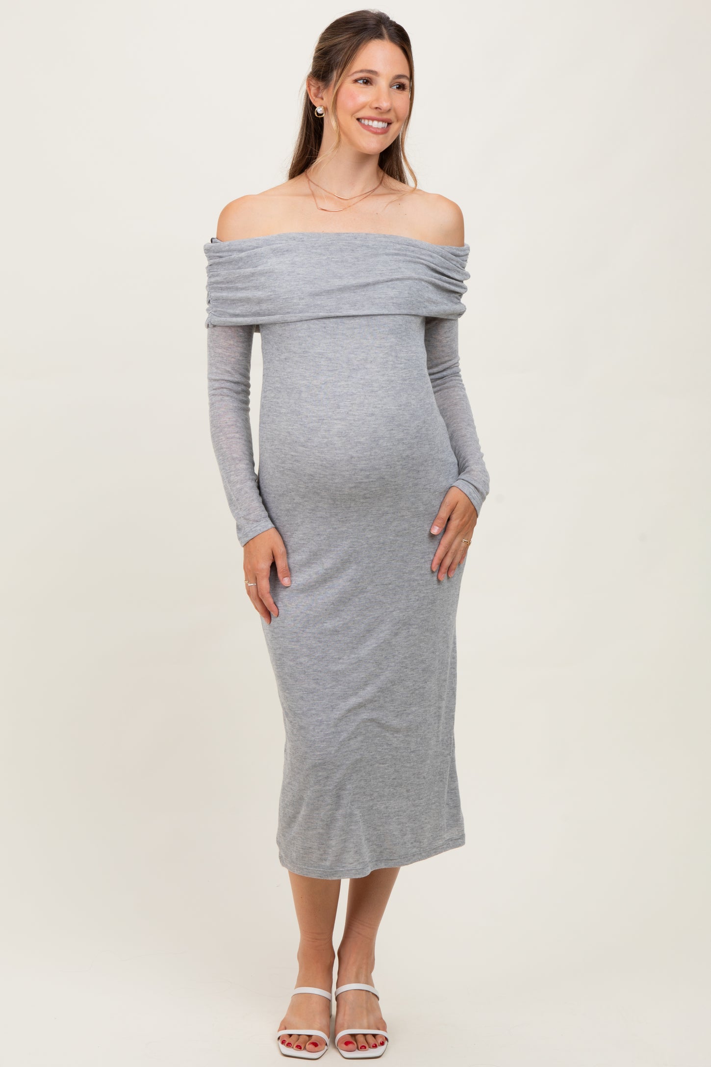 woman wearing a grey off-shoulder maternity dress with long sleeves and a visible baby bump