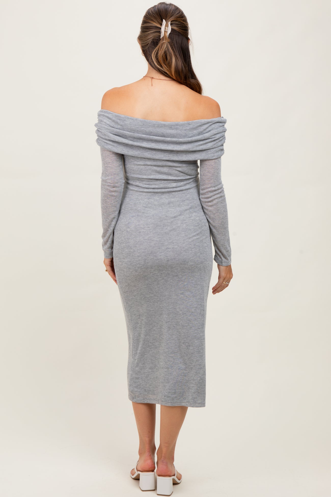 woman wearing a gray off-shoulder maternity dress with long sleeves and a fitted midi length
