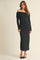 woman wearing a black off-the-shoulder long sleeve midi dress with a fitted silhouette and side slits
