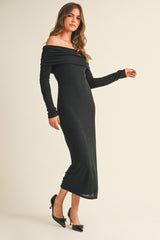 woman wearing a black off-the-shoulder long sleeve dress, styled with a fitted silhouette and high slit, paired with black heels