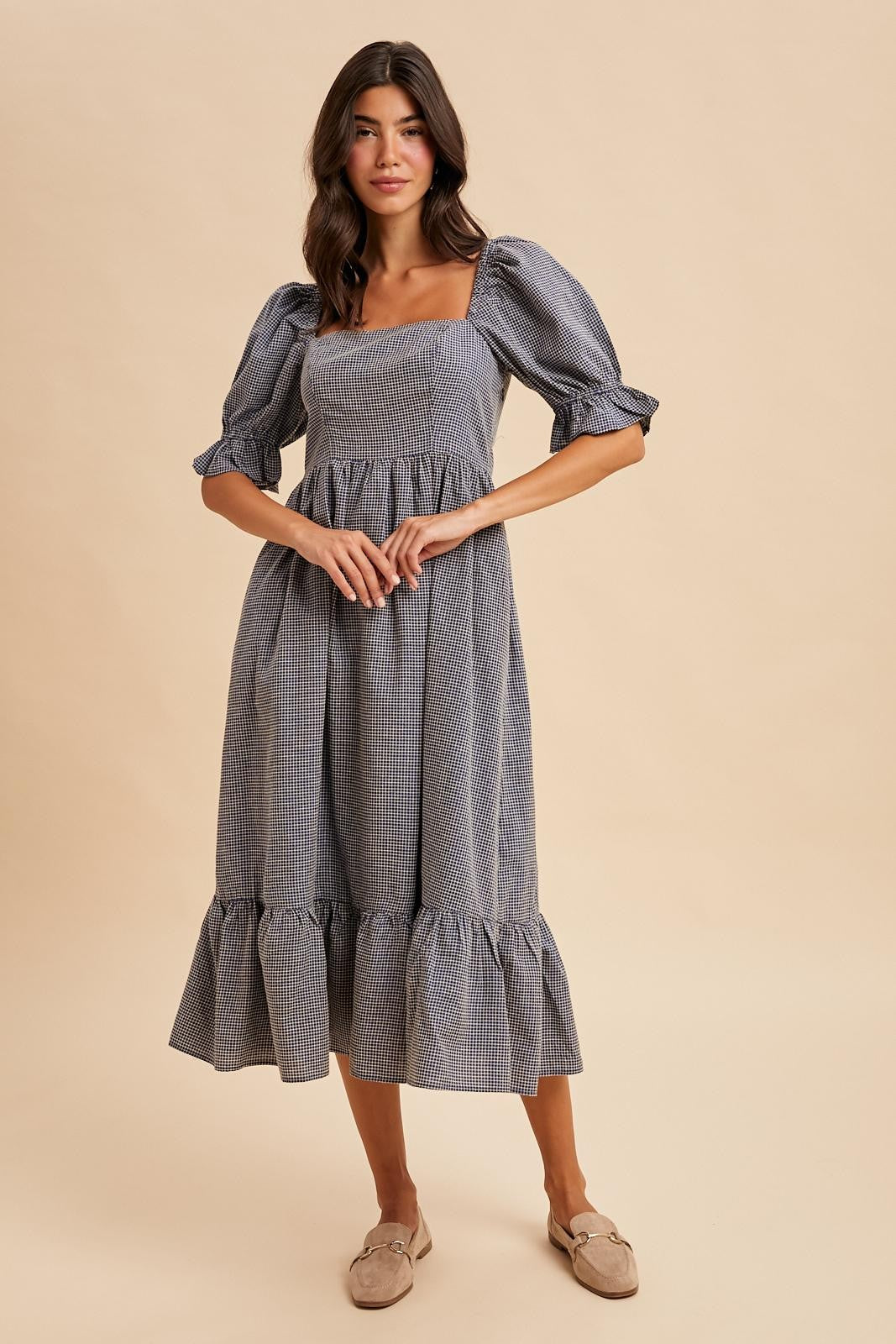 woman wearing a blue and white gingham midi dress with puff sleeves and a tiered hem