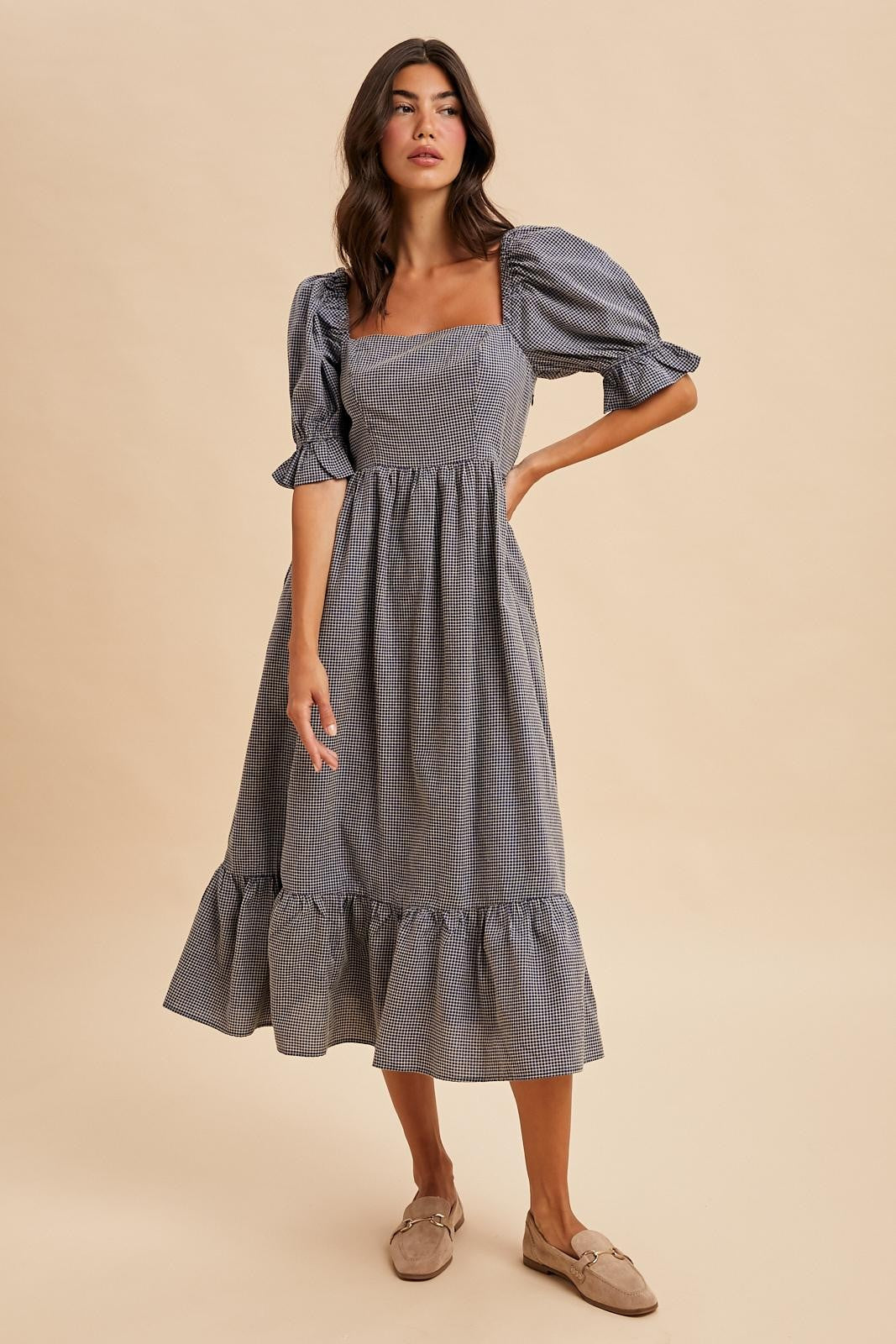 woman wearing a blue and white checkered midi dress with puff sleeves and a ruffled hem