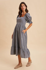 woman wearing a gray checkered midi dress with puff sleeves and a ruffled hem, styled with beige flats