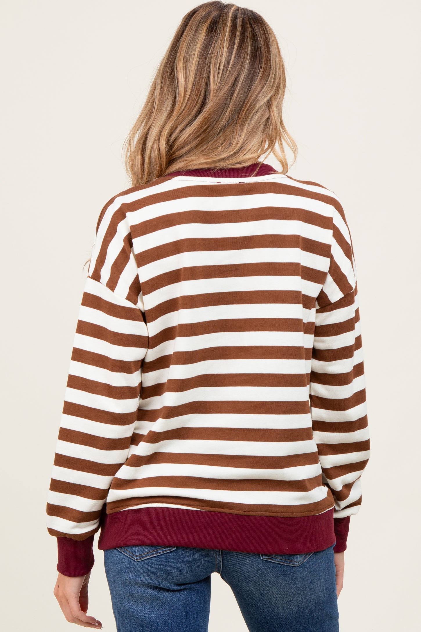 woman wearing a brown and white striped maternity sweatshirt with a maroon waistband and cuffs, viewed from the back