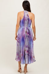 woman wearing a sleeveless purple and blue pleated maxi dress with a halter neck and flowing hemline