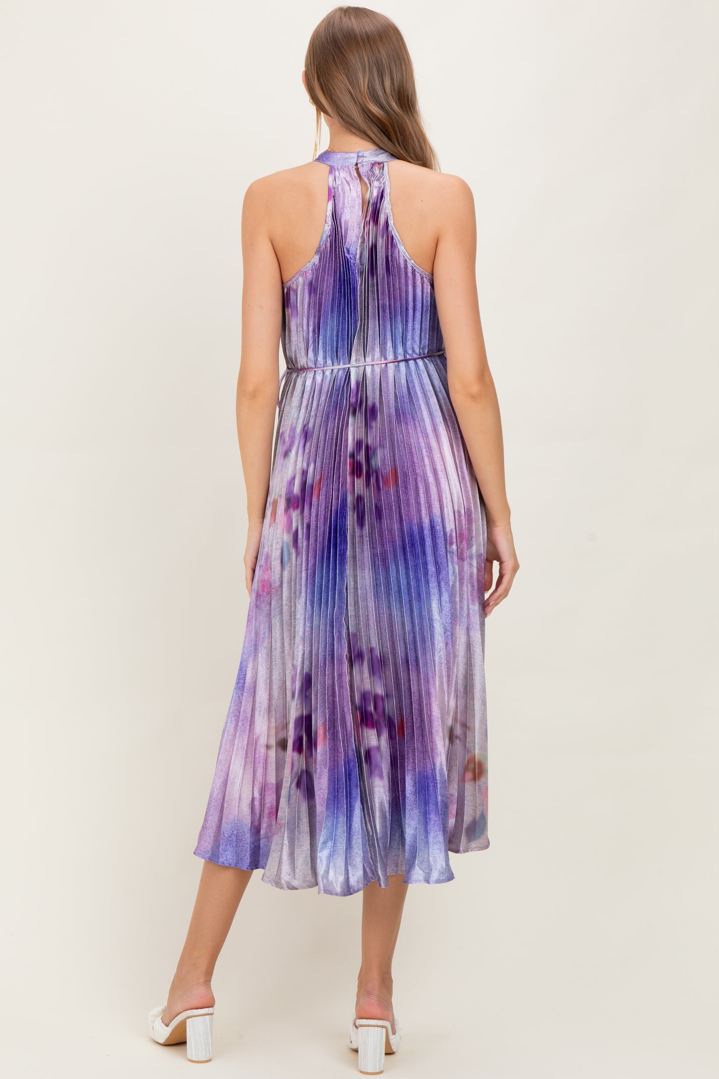 woman wearing a purple and blue tie-dye maternity dress with pleats and a halter neck, showing her baby bump