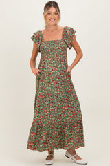woman wearing a floral print green maternity maxi dress with ruffle sleeves and pockets, standing against a neutral background